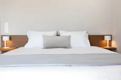 a white bed with white pillows and two lamps at Alinea Suites Limassol Center in Limassol