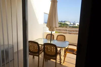 a glass table and chairs in a room with a balcony at Nissi Elena -Sunshine Apt in Ayia Napa