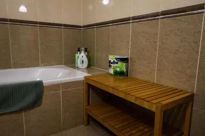 a bathroom with a bath tub and a wooden table at Nissi Elena -Sunshine Apt in Ayia Napa