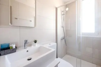 a white bathroom with a sink and a shower at The Habitat Mediterraneo - Self Check-in in Larnaka