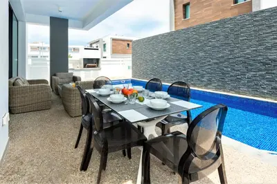 a dining room with a table and chairs next to a pool at Villa Mirella in Protaras