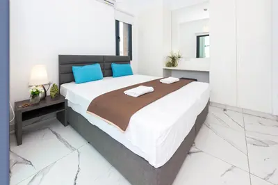 a white bedroom with a large bed with blue pillows at Villa Mirella in Protaras