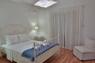 a white bedroom with a bed and a chair at Nestor Hillside House by TrulyCyprus in Moniatis