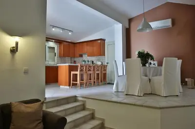 a kitchen and living room with a table and chairs at Nestor Hillside House by TrulyCyprus in Moniatis