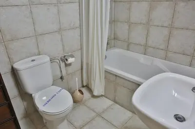 a bathroom with a toilet and a sink and a tub at Nestor Hillside House by TrulyCyprus in Moniatis