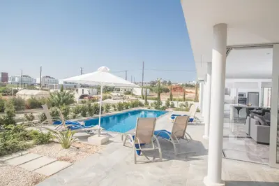 a swimming pool with two chairs and an umbrella at Blue Pearl Villas in Protaras