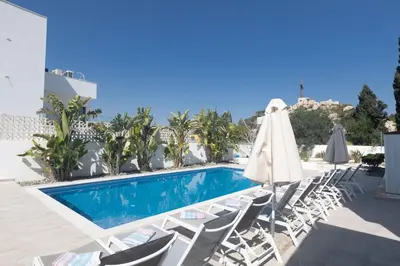 a swimming pool with lounge chairs and an umbrella at Rosie Villa in Ayia Napa