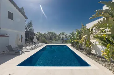 a swimming pool with chairs and a house at Rosie Villa in Ayia Napa