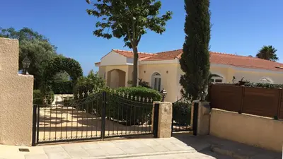 a fence in front of a house with a tree at Sunset Cliff Villa Panoramic Sea Views Private Heated Pool Included in Pissouri