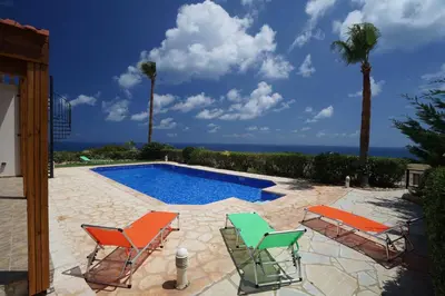 a patio with chairs and a swimming pool at Sunset Cliff Villa Panoramic Sea Views Private Heated Pool Included in Pissouri