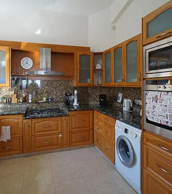 a kitchen with wooden cabinets and a washer and dryer at Sunset Cliff Villa Panoramic Sea Views Private Heated Pool Included in Pissouri