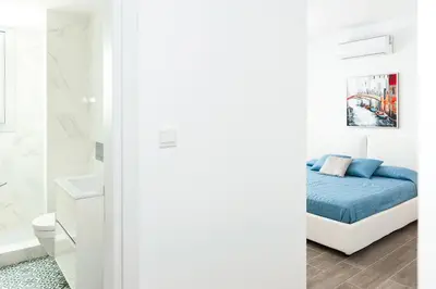 a white bedroom with a bed and a bathroom at Villa Sunday in Ayia Napa