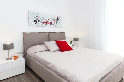 a white bedroom with a large bed with a red pillow at Villa Sunday in Ayia Napa