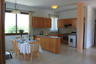 a kitchen with a table and chairs and a kitchen with a stove at Yiannos House in Evrykhou