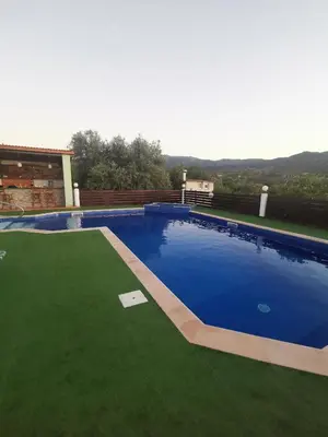 a large blue swimming pool with green grass at Yiannos House in Evrykhou