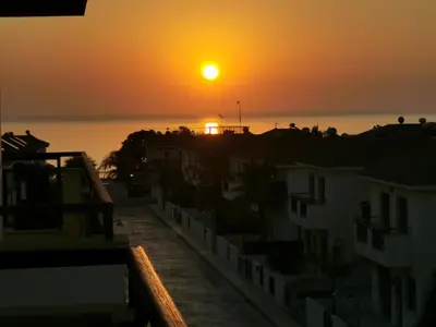 a sunset over the ocean with houses and buildings at Sea view apartment in Protaras