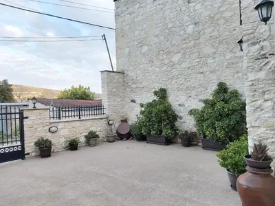 a courtyard with potted plants and a stone wall at Omodos Maria's Apartments in Omodos