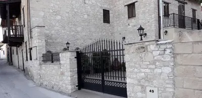 a stone building with a black gate on a street at Omodos Maria's Apartments in Omodos
