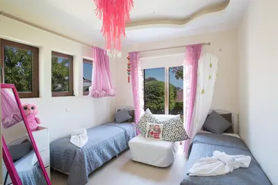 a bedroom with two beds and pink curtains at Oscar Domain Villa in Protaras