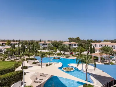 an aerial view of a resort pool with palm trees at Atlantis Gardens in Mazotos