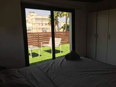 a bedroom with a bed and a window with a chair at Town centre suites in Larnaka