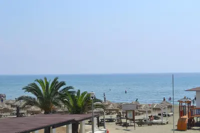 a beach with chairs and umbrellas and the ocean at 13 Sandy Beach Mackenzie in Larnaka