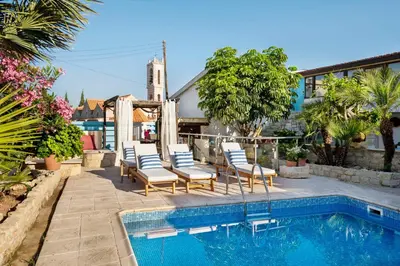 a swimming pool with chairs next to a house at Cottage Houses in Pendakomo