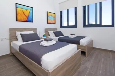 two beds in a room with windows at Villa Melody in Protaras
