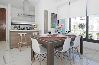 a kitchen and dining room with a wooden table and white chairs at Villa Melody in Protaras