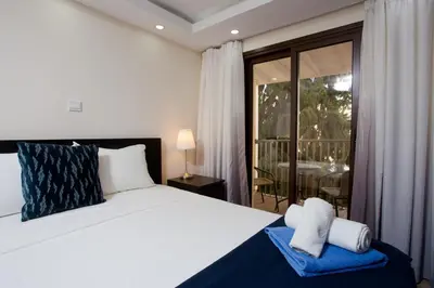a bedroom with a large bed and a balcony at Galatex Beach Living by TrulyCyprus in Limassol
