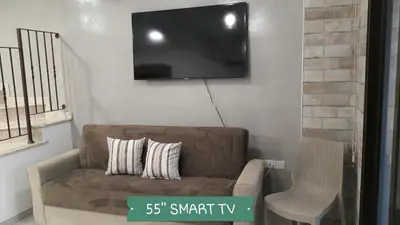 a living room with a couch and a tv on the wall at CHRIS'S KYKLADES HOLIDAY APARTMENT in Paralimni