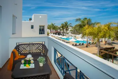 a balcony with a table and a view of the pool at Flouressia Gardens in Protaras