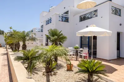 a white house with palm trees and an umbrella at Flouressia Gardens in Protaras