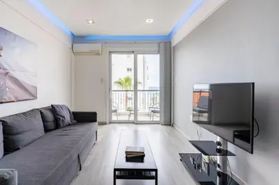 a living room with a couch and a flat screen tv at Must Stay - Finikoudes Seaview in Larnaka