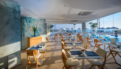a restaurant with tables and chairs and a pool at Infinity Blu - Designed for Adults by Louis Hotels in Protaras