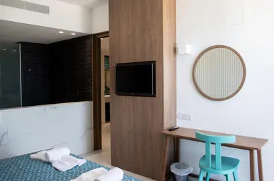 a bedroom with a bed and a mirror and a stool at Mandali Hotel in Protaras