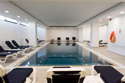 a pool in a room with chairs and a swimming pool at Mandali Hotel in Protaras