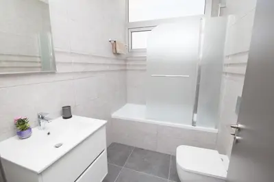 a white bathroom with a sink and a toilet at Villa Lynn Boutique Beachfront in Ayia Napa