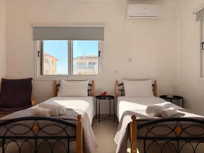two twin beds in a room with a window at Lovely holiday home,Kapparis,2 swimming pools,Wifi in Paralimni