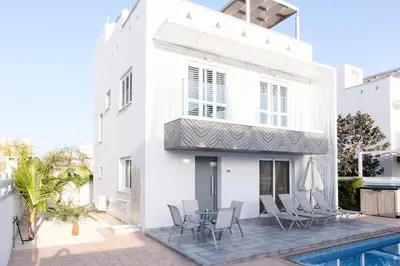 a white house with a patio and a swimming pool at Nissini Blanco, 3 bedroom villa with private pool, 5 min to the beach in Ayia Napa