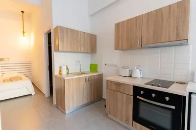 a small kitchen with wooden cabinets and a bed at Prima Gardens City Studios in Larnaka