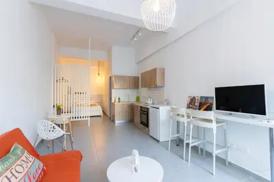 a kitchen and living room with a couch and a tv at Prima Gardens City Studios in Larnaka
