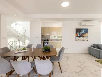 a dining room and living room with a table and chairs at Milos lifestyle villa H30 in Protaras