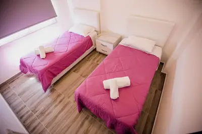 two beds in a small room with pink sheets at Twins Apartments in Kato Pyrgos