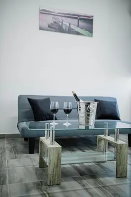a living room with a blue couch and two glasses of wine at Twins Apartments in Kato Pyrgos