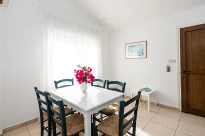 a white table with chairs and a vase of flowers on it at Fig Tree Z Holiday Resort in Paralimni