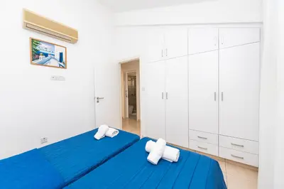 a bedroom with a blue bed and white cabinets at Fig Tree Z Holiday Resort in Paralimni