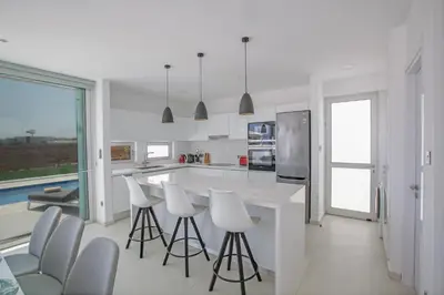 a kitchen with white counters and white stools at Villa Alana in Protaras