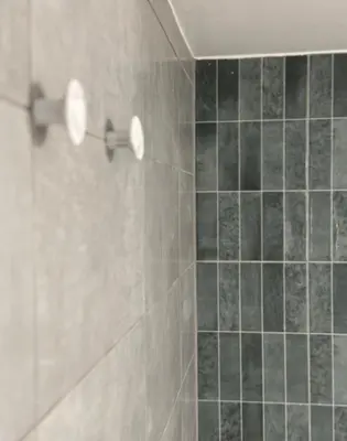 a shower with black tiles and two lights on the wall at Krasas Beach in Larnaka