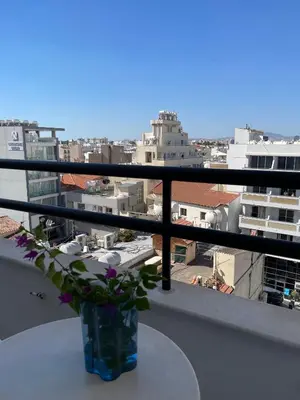 a vase with flowers sitting on a table on a balcony at Krasas Beach in Larnaka
